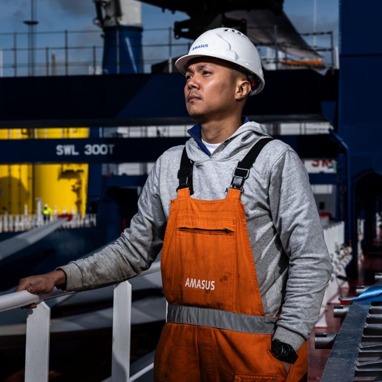 Offshore-mederker-staat-bakboordzijde-kijkend-over-scheepsdek