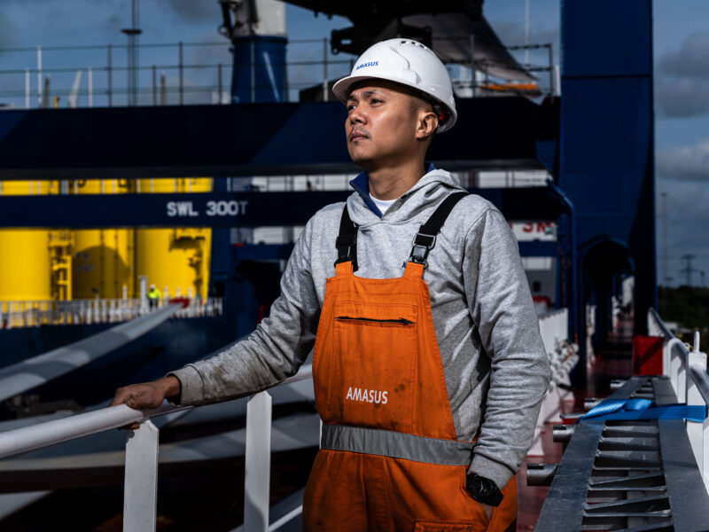 Offshore-mederker-staat-bakboordzijde-kijkend-over-scheepsdek