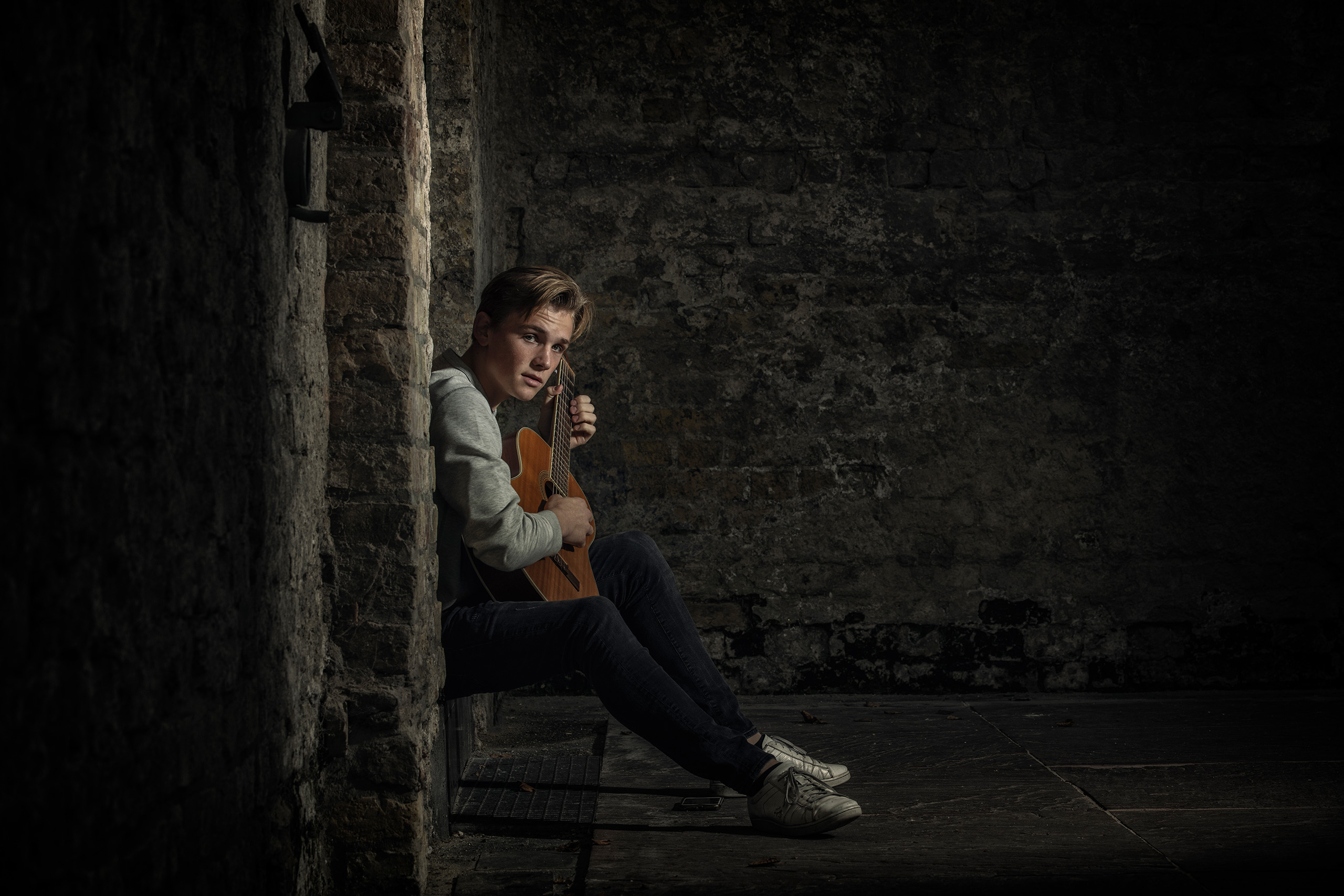 Portret van jongen met gitaar zittend in een nis, gefotografeerd door Daniel Wenzel Fotografie