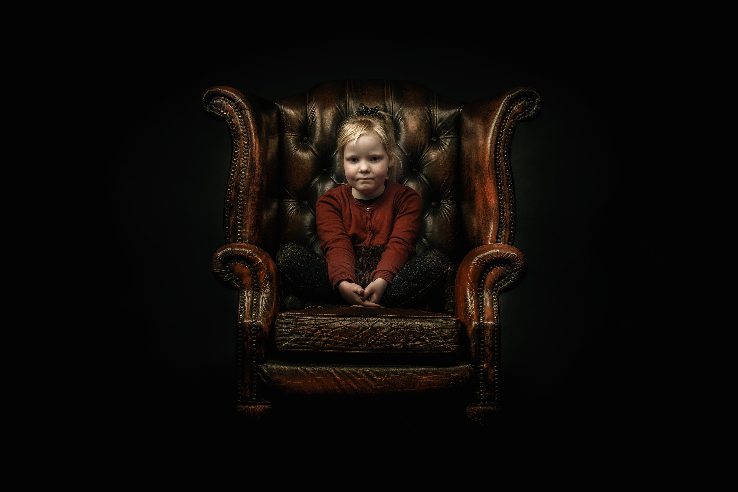 Portretfoto van meisje op Chesterfield stoel gefotografeerd door Daniel Wenzel Fotografie
