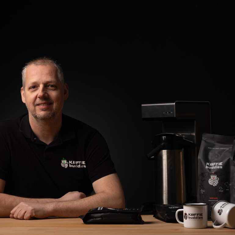 Eigenaar koffiebuddies aan tafel met zijn producten