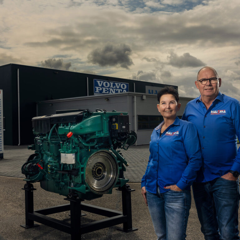 Directie, man en vrouw poseren voor hun bedrijf in Harlingen naast een Volvo Penta motorblok